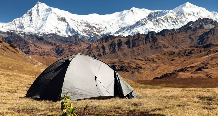 Una tienda de campaña situada frente a una vista impresionante de montañas cubiertas de nieve.