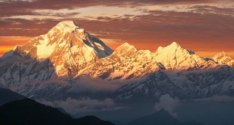 Una vista dramática del atardecer sobre picos montañosos cubiertos de nieve.