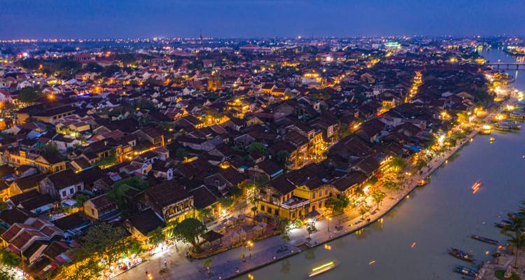 Hoi An iluminado por la noche con un río que atraviesa la ciudad.