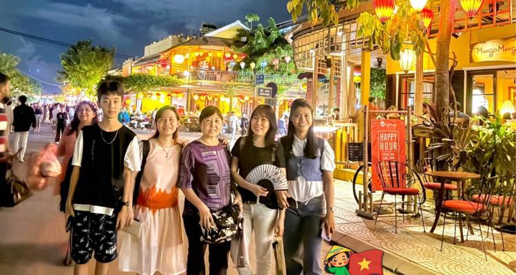 Le groupe profite de la rue de Hoi An éclairée par des lanternes la nuit avec un autocollant du Vietnam en superposition.