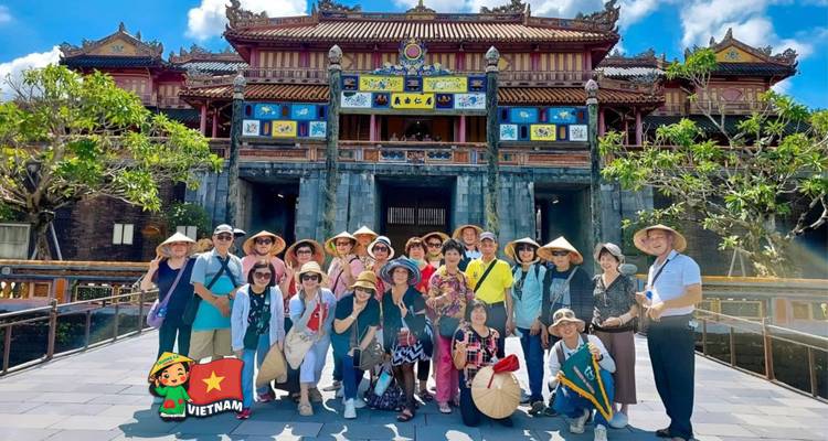 Grand groupe de touristes pose à la porte de la Citadelle impériale de Hué, filigrane d'autocollant Vietnam présent.
