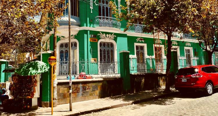 Scène de rue colorée montrant un bâtiment vert et divers éléments urbains.