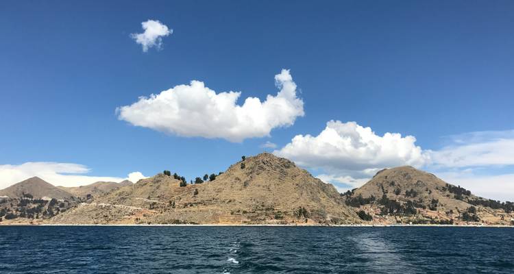 Vue d'horizon d'une île montagneuse et de la mer sous un ciel bleu avec des nuages.
