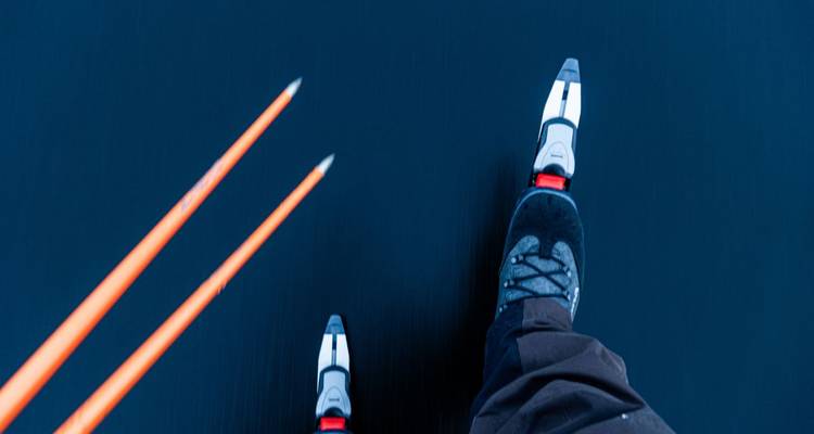 Gros plan de patins à glace sur une surface gelée avec des bâtons de ski.