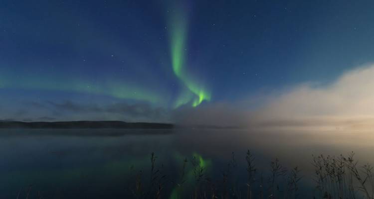 Aurores boréales illuminant le ciel au-dessus d'un lac serein.