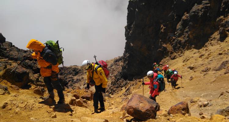 Group of hikers ascending a steep rocky slope.