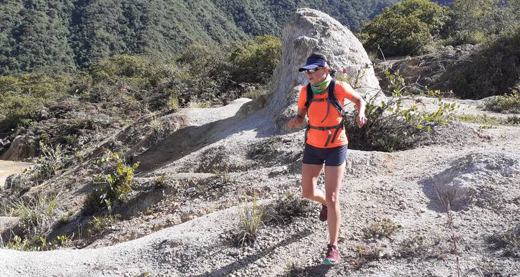 Frau, die auf einem steinigen Pfad inmitten der Natur joggt.
