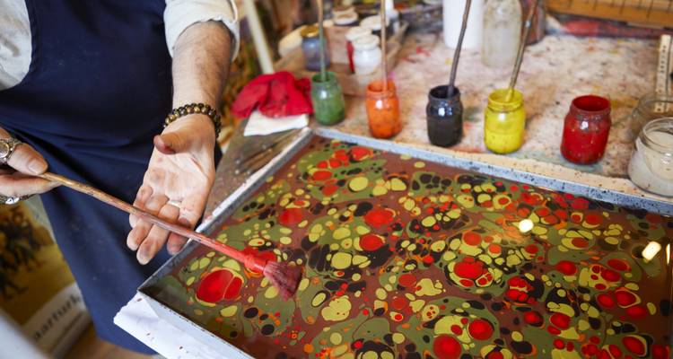 Personne démontrant l'art de la peinture Ebru turque avec des couleurs vives sur un plateau.