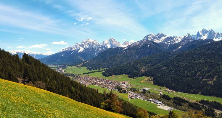 Tal mit einer Stadt, umgeben von schneebedeckten Bergen.