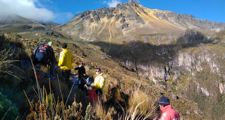 Gruppe von Menschen, die auf einem Bergpfad mit schroffer Berglandschaft rasten.