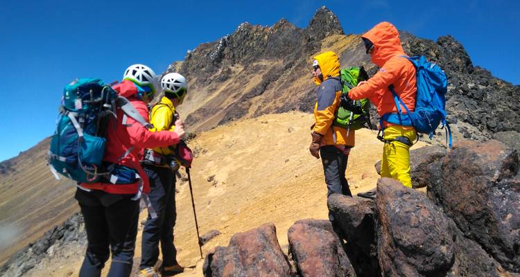 Gruppe von Wanderern in bunter Ausrüstung, die auf einem felsigen Bergpfad wandern.