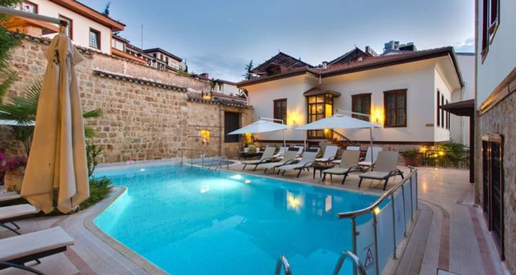 Hotelzwembadgebied met ligstoelen en parasols bij zonsondergang.