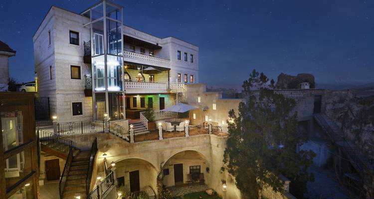 Nachtelijk zicht op een verlicht hotelgebouw met terrassen en bogen.
