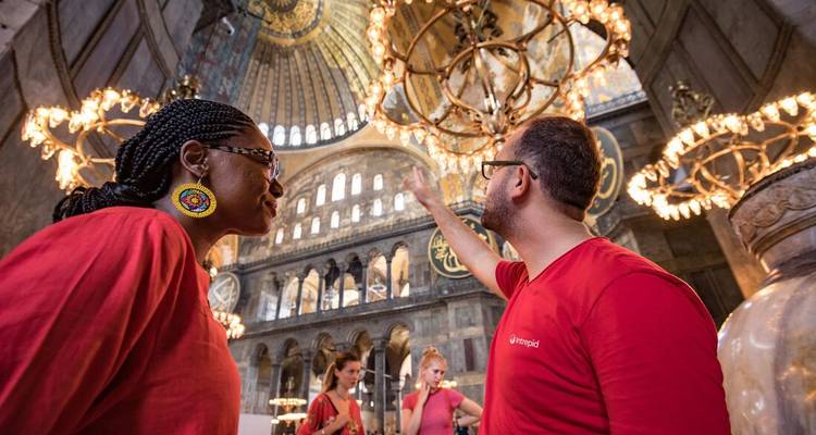 Bezoekers in rode shirts die de sierlijke kroonluchters en hoge koepels in de Hagia Sophia bewonderen