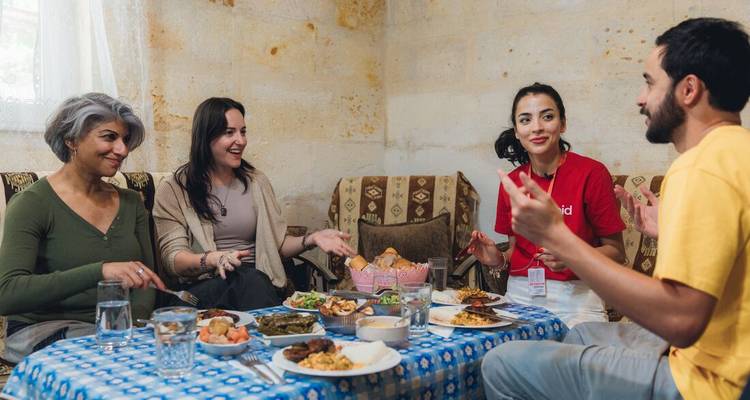 Reizigers die een zelfgekookte maaltijd delen rond een lage tafel in een stenen Cappadocisch huis