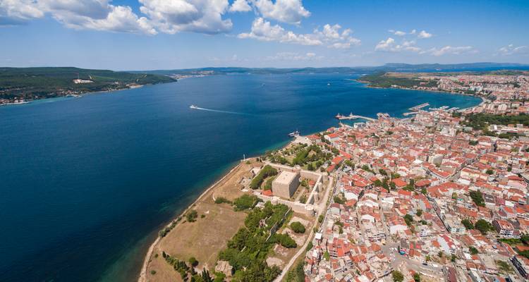 Luchtfoto van de stad Çanakkale en de waterkant langs de Dardanellen met een historisch fort en drukke haven.