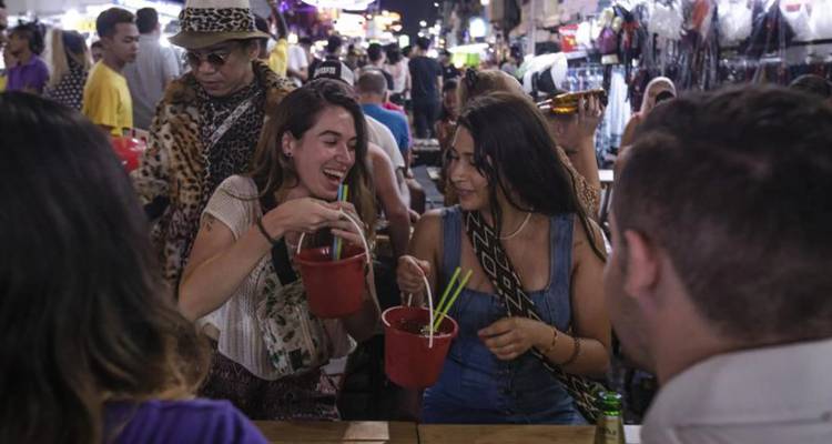 Young adults enjoying nightlife with drinks in red buckets.