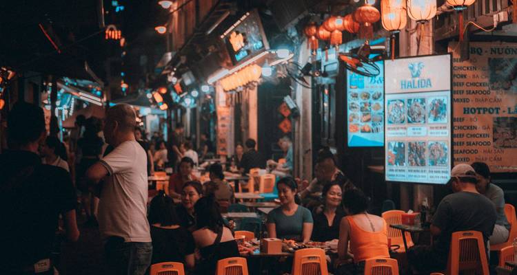 Bustling night market street scene with many people dining.