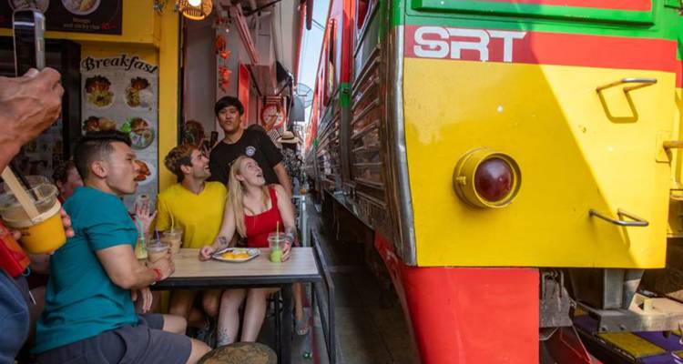 Des amis savourant un verre à côté d'un train SRT coloré.