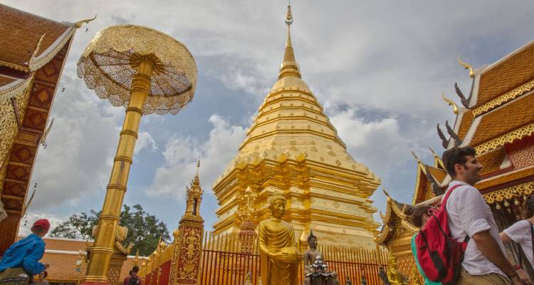 Temple bouddhiste doré avec des détails ornementés et une statue au premier plan.