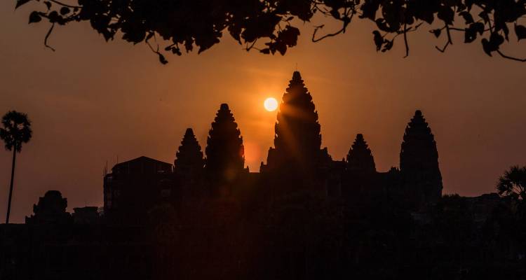 Silueta de Angkor Wat contra una puesta de sol con efecto de rayos solares.