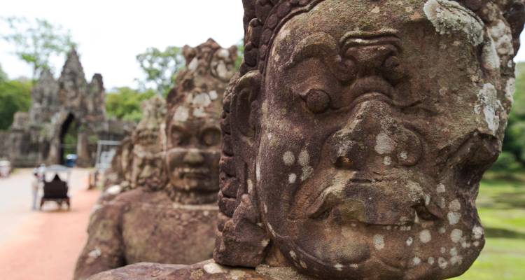 Tallados detallados en piedra de figuras antiguas, con enfoque principal en un rostro grande.