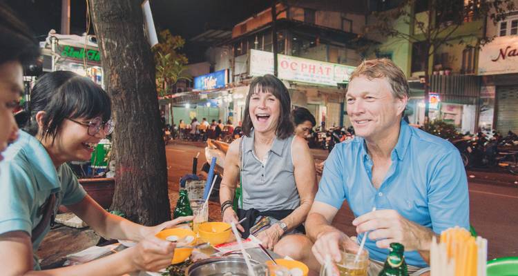 Groep mensen die genieten van een maaltijd bij een eetgelegenheid aan de straat.