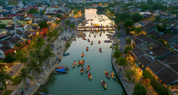 Luchtfoto van een rivier met boten en mensen op de oevers.