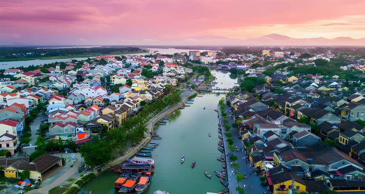 Kleurrijke huizen en een kalme rivier onder een levendige zonsondergang.