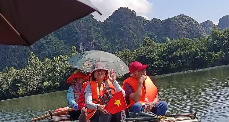 Groupe sur un bateau avec un drapeau vietnamien, profitant d'une promenade en rivière.