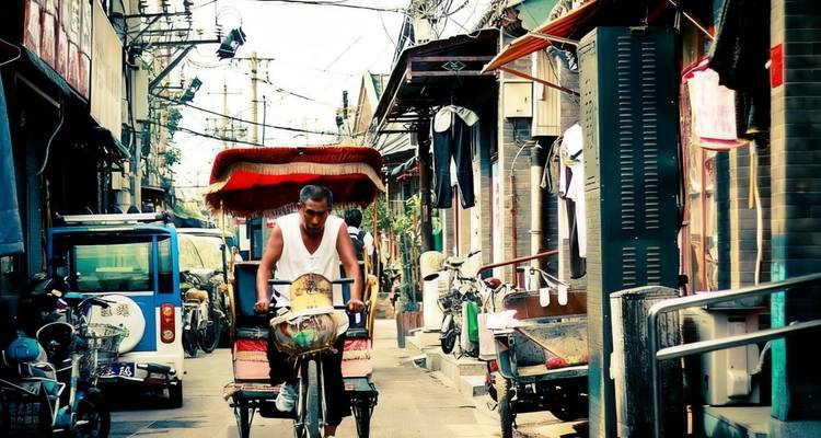 Man cycling through a busy street in a residential area.
