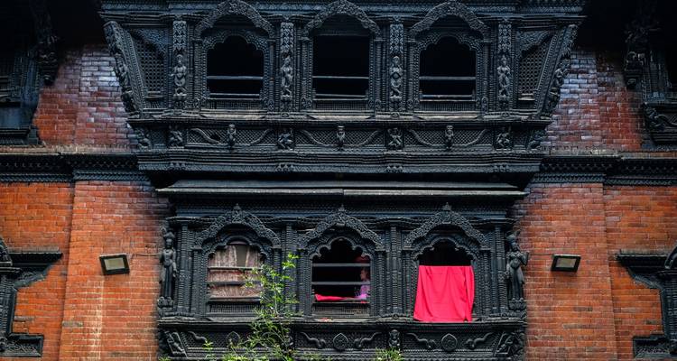 Sculptures ornementées de fenêtres noires sur bâtiment en briques rouges.