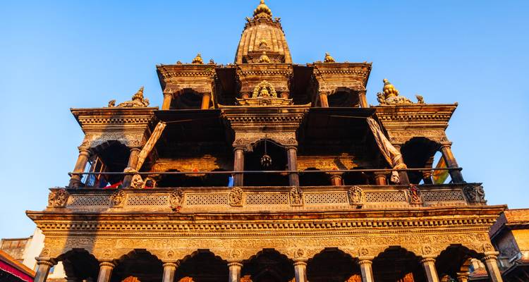 Une vue détaillée d'un temple traditionnel de style pagode avec des sculptures complexes et des statues dorées.