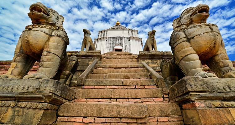 Un escalier flanqué de statues de lions en pierre menant à un temple.