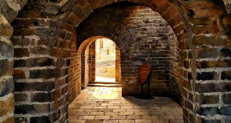 Inside a stone tunnel on the Great Wall of China with natural light seeping in.