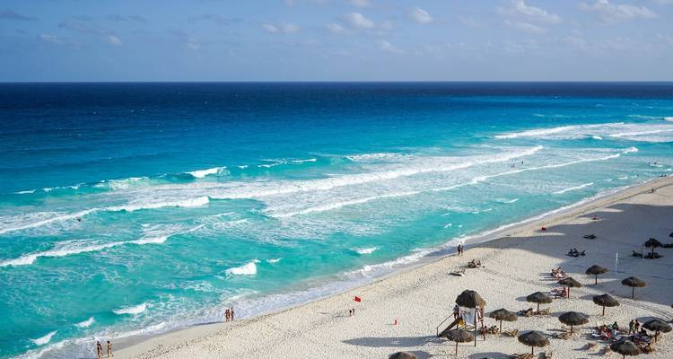 A pristine beach with turquoise water and beach umbrellas.