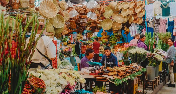 A vibrant market scene with flowers and woven goods for sale.