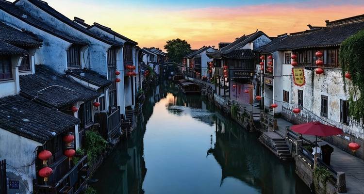 A picturesque canal flanked by traditional Chinese buildings at sunset.