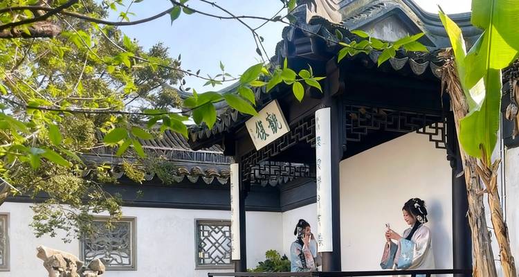 Two women in traditional attire on a terrace of a Chinese garden.