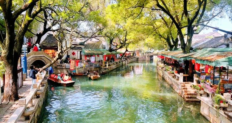 Vibrant and busy canal scene with boats and outdoor markets.