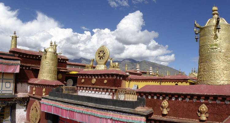 Ornate golden roofs and structures with a mountainous backdrop.