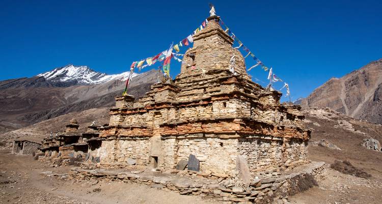 Un stupa en pierre orné de drapeaux de prière situé dans une région montagneuse.