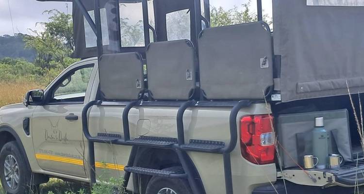 A safari vehicle with several seats in a grassy area.