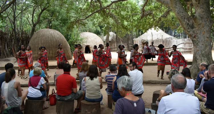 Cultural dance performance with people watching seated outdoors.