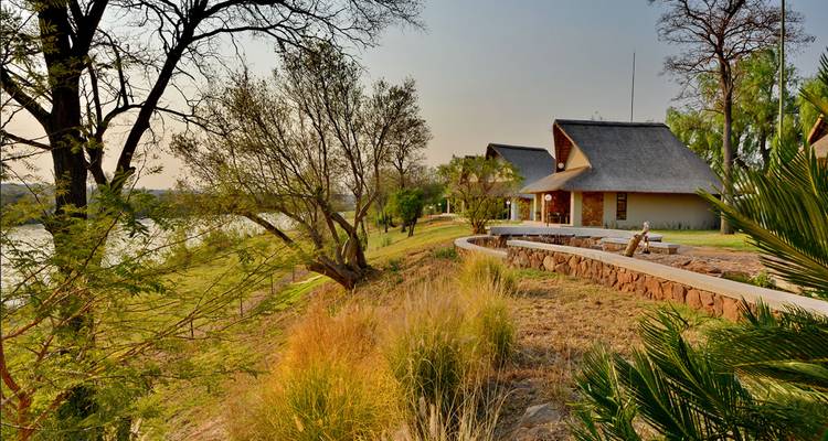 Lodge exterior with thatched roofs and a view of the landscape.