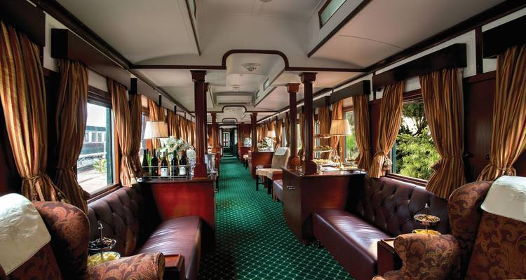 Interior of a luxurious train with plush seating and ornate decor.