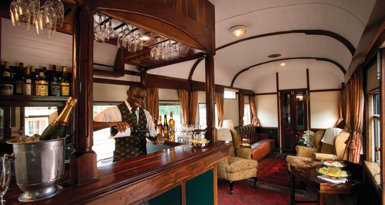 Bartender serving a drink inside a lavish train bar.