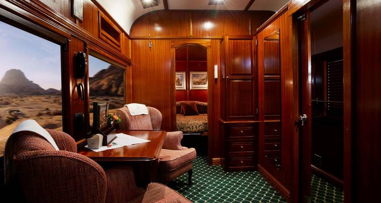 Interior of a train cabin with seating and views of the landscape.