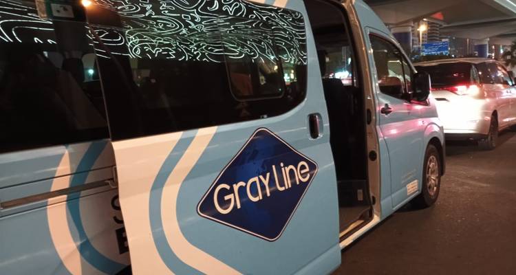 Un fourgon de visite Gray Line la nuit dans un environnement urbain.