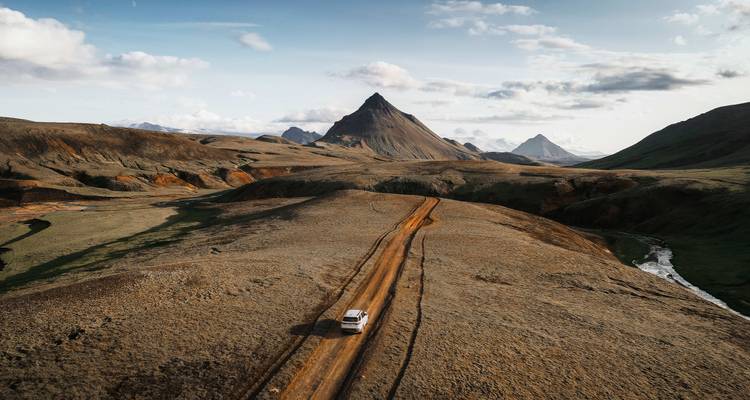 Un vehículo en un camino de tierra en un paisaje montañoso remoto.